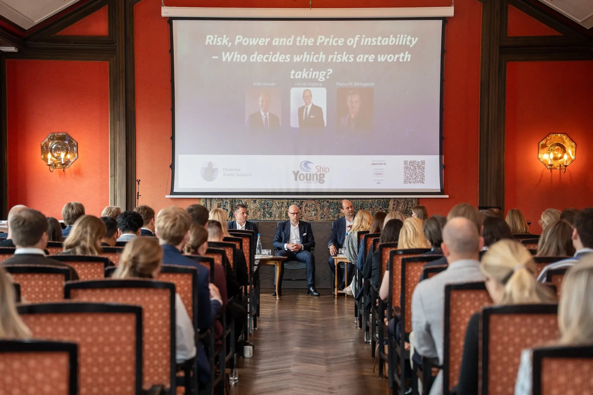 Paneldebatt med tre innledere på scene foran et publikum i en konferansesal
